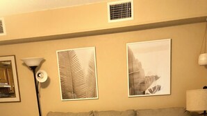 A hotel room with a large bed, two pillows, a side table with a vase and a book, and wall art. - Cozy studio in wonderful New Smyrna Beach walking distance to 27th ramp and park (New Smyrna Beach)
