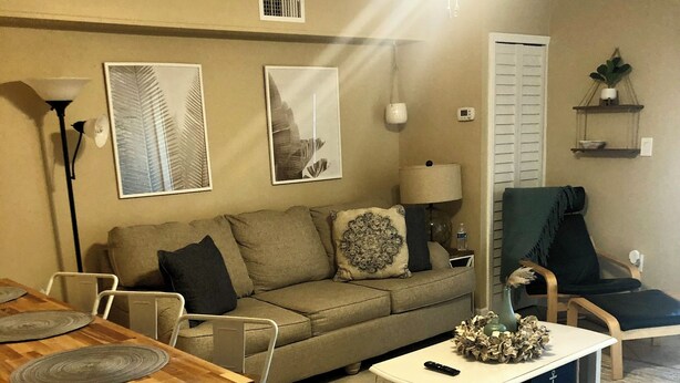 A living room with a sofa, coffee table, and a dining area with chairs and a table. - Cozy studio in wonderful New Smyrna Beach walking distance to 27th ramp and park (New Smyrna Beach)
