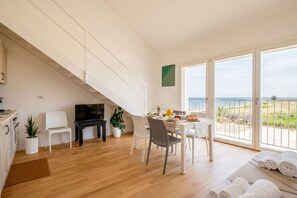 Una sala de estar moderna con comedor, televisor y balcón con vistas.