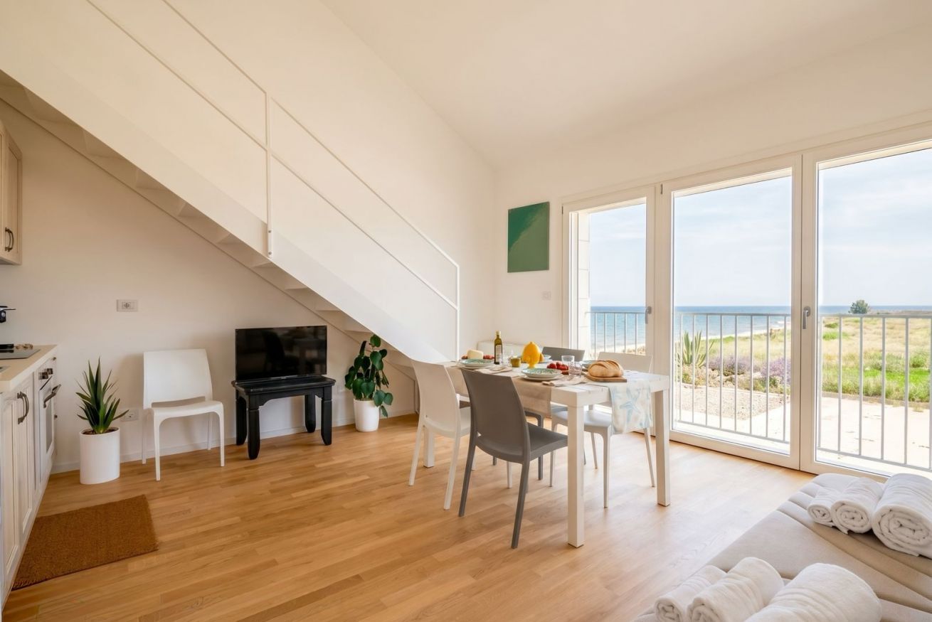 A modern living room with a dining area, a TV, and a balcony with a view.