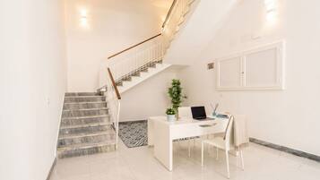 Un intérieur moderne avec un escalier, un bureau avec un ordinateur portable et une plante en pot.