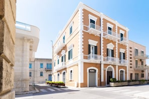 A multi-story building with balconies, a prominent entrance, and a clear sky.
