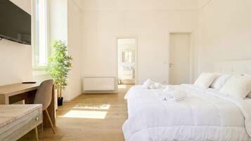 Une chambre à coucher avec un lit, un bureau, une chaise, une plante en pot et un téléviseur.