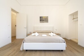 A bedroom with a bed, a nightstand, a painting, and a door.