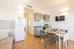 A modern kitchen with a built-in oven, a dining area with a table and chairs, and a TV mounted on the wall. - Benjamin House with Private Parking (Bari)