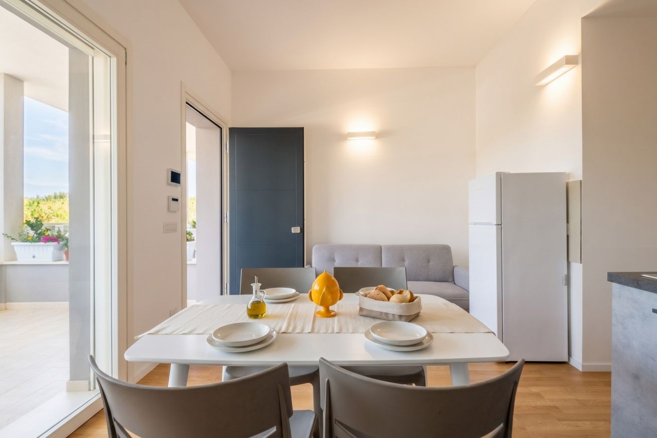 Eine moderne Küche mit Essbereich, ein graues Sofa und Blick ins Grüne.