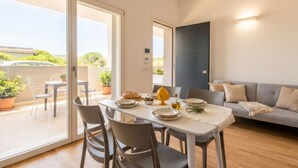 Un coin repas avec une table dressée pour deux personnes, un canapé et une vue sur l’extérieur.