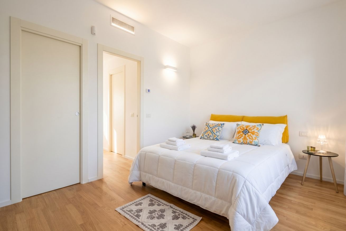 Ein Schlafzimmer mit einem Bett, einem Nachttisch, einer Lampe und einer Tür.
