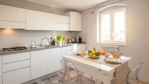 A modern kitchen with white cabinets, a gas stove, a sink, and a dining area with a table set for two.