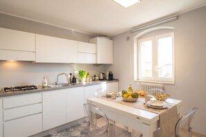 A modern kitchen with white cabinets, a gas stove, a sink, and a dining area with a table set for two.