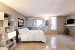 A modern bedroom with a bed, built-in shelving, a radiator, and a TV.