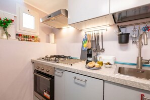 A modern kitchen with a gas stove, oven, stainless steel sink, and various utensils.