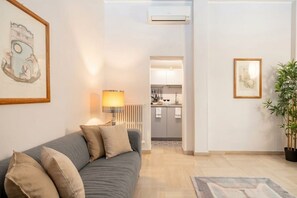 Uma sala de estar moderna com um sofá cinza, uma luminária e um quadro na parede.