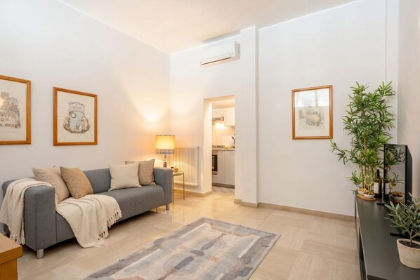 A modern living room with a grey sofa, a coffee table, a lamp, and framed artwork on the walls.