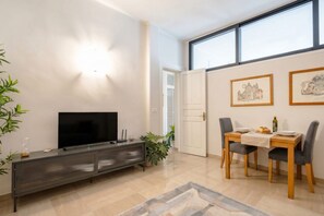 Uma sala de estar moderna com televisão de tela plana, mesa de jantar com cadeiras e obras de arte nas paredes.