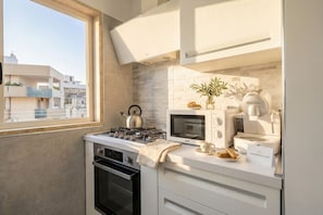 A compact kitchen with a gas stove, oven, microwave, and coffee maker.
