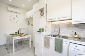 A modern kitchen with white cabinetry, a stainless steel sink, and a Samsung dishwasher.