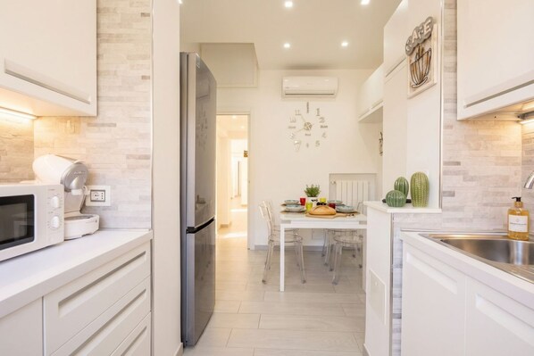 A modern kitchen with a refrigerator, microwave, and a dining area with a table and chairs.