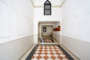 A corridor with a checkered floor, white walls, a window with bars, and a door at the end. - Casa di Carly - large cozy retreat in center (Bari)