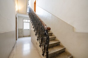 A staircase with a wooden handrail and metal balusters, leading to a door with a window.