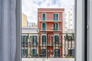 Um edifício de vários andares com varandas, guarda-corpo de metal e céu claro.