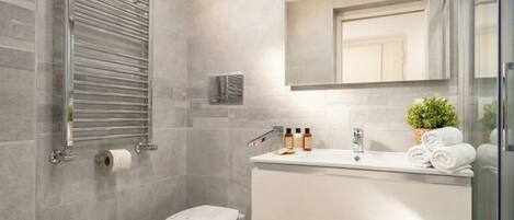 A modern bathroom with a glass shower enclosure, a toilet, a vanity with a mirror, and a towel rack.