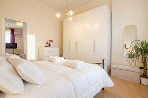 A bedroom with a bed, a wardrobe, a mirror, and a potted plant. - Carlotta - Italian Living (Bari)