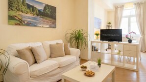 A living room with a sofa, a coffee table with snacks, a TV, and a painting of a river.