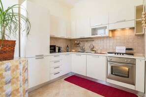 A modern kitchen with white cabinets, a microwave, an oven, and a red rug. - Carlotta - Italian Living (Bari)
