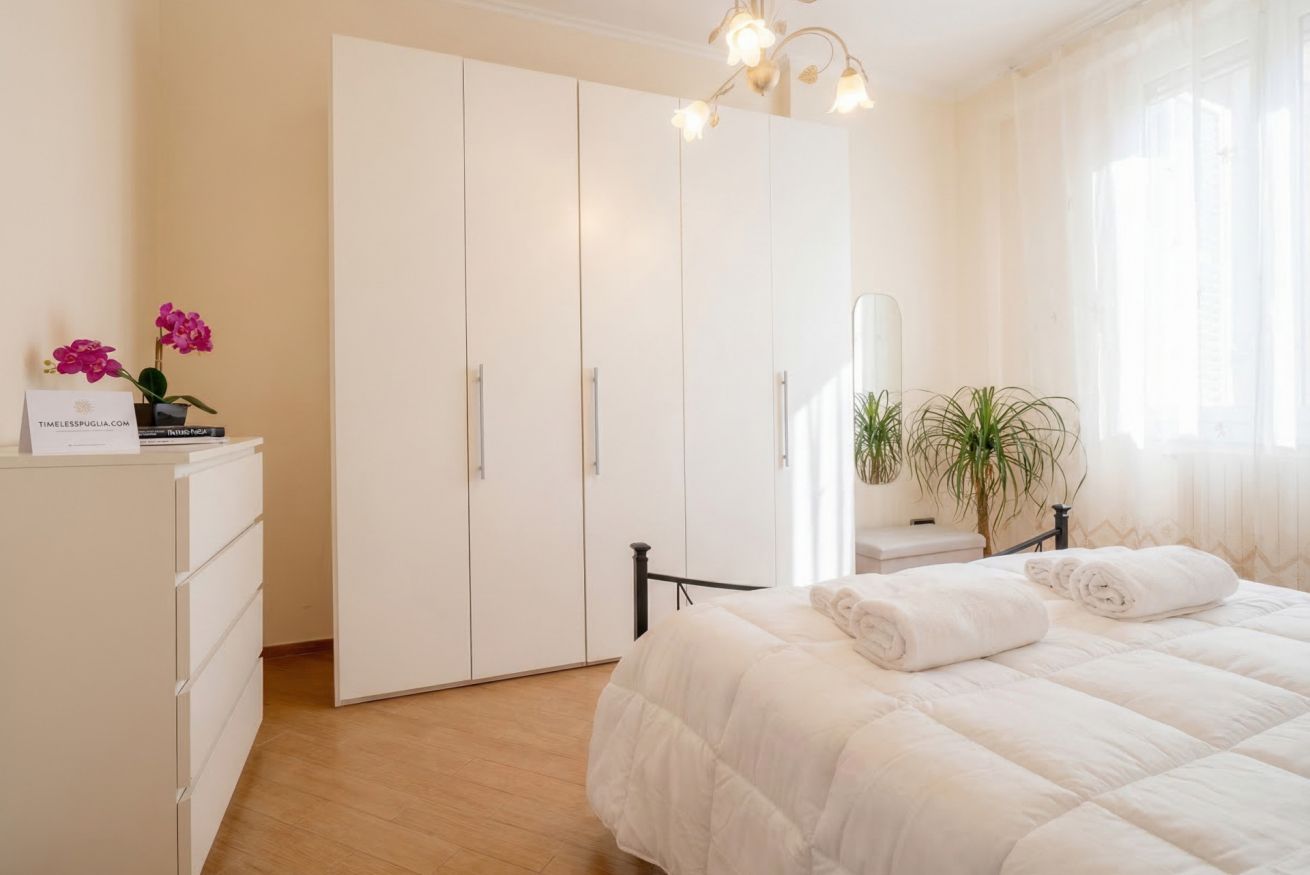 Une chambre à coucher avec un lit, une armoire, un bureau avec une plante et un miroir.