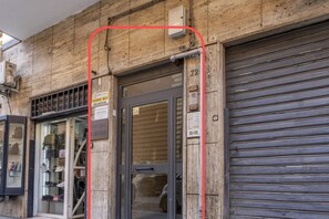 A storefront with a glass door, a metal shutter door, and a sign indicating a sale.