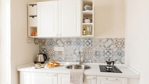 A kitchen with white cabinets, a tiled backsplash, a sink, and a kettle. - Alba Suite Apartment (Bari)