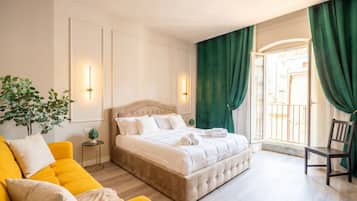 Une chambre d’hôtel avec un lit, un canapé jaune, une chaise et une fenêtre avec des rideaux.