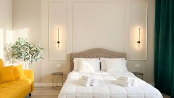 Un dormitorio ordenado con una cama, dos mesitas de noche, un florero y un sofá amarillo.