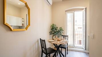 Un coin repas avec une table ronde, des chaises noires, un miroir et une plante en pot.