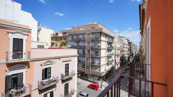 Una strada cittadina a più piani con edifici, balconi e auto parcheggiate.