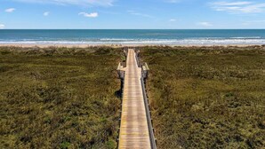 A wooden boardwalk leading to a beach with a clear view of the ocean.