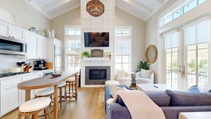 A spacious kitchen with a central island, a fireplace, and a cozy seating area with a sofa and chairs.