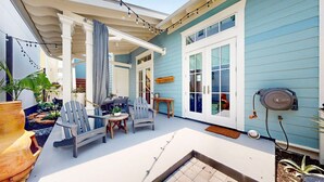 A covered patio area with outdoor furniture, a pergola, and string lights.