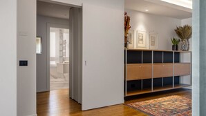 Een moderne hal met een houten vloer, een kamerbreed tapijt en een inbouwkast met kunstwerken en decoratieve planten.
