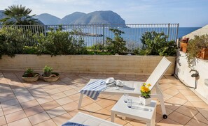 A terrace with a white lounge chair, a small table, and potted plants. - Blue Wave Addaura by DomuSicily (Palermo)
