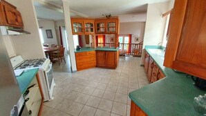 A kitchen with wooden cabinets, a gas stove, and a dining area with chairs and a table. - Sérenité. Vigie (Castries)