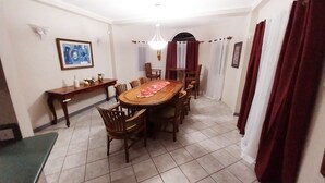 A dining area with a wooden table and chairs, a bench, a small side table, and a hanging light fixture. - Sérenité. Vigie (Castries)