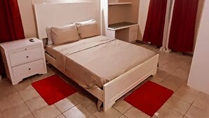 A bedroom with a bed, a nightstand, a wardrobe, and a shelf unit. - Sérenité. Vigie (Castries)