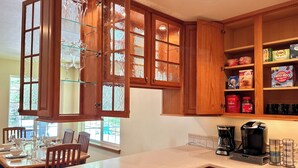 A kitchen with wooden cabinets, a countertop, and a dining area with chairs and a table set for a meal.