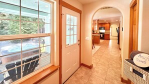 A hallway with a door leading to a kitchen area, a dining area with a table and chairs, and a wicker basket labeled "Beach Towels".