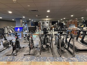 Un gimnasio con cintas de correr, bicicletas estáticas y máquinas de pesas.