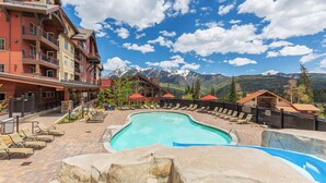 A pool area with lounge chairs, a stone pool, and a mountain backdrop.