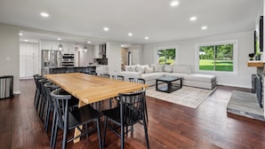A spacious living area with a wooden dining table, black chairs, a sofa, and a fireplace.