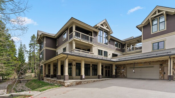 Ein mehrstöckiges Haus mit überdachter Veranda, geräumiger Garage und Auffahrt.